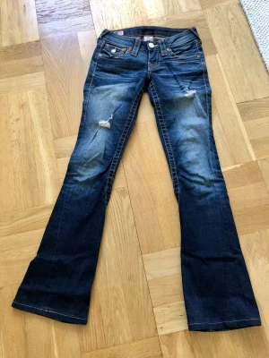 True Religion Jeans, st: 24 - Så snygga byxor från True Religion i storlek 24. Lowrise and bootcut! Innerbenslängd: 75cm. Bra skick!