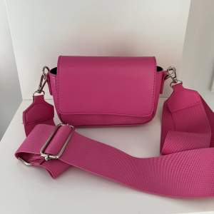 Säljer denna rosa mini väska som är perfekt att ha sina kort och mobil i till sommaren! Oanvänd och kommer inte till användning! Går även att ta av bandet och trä igenom det på baksidan för att ha den som en midjeväska🌸🌸Färgen ser lite mörkare ut på bild