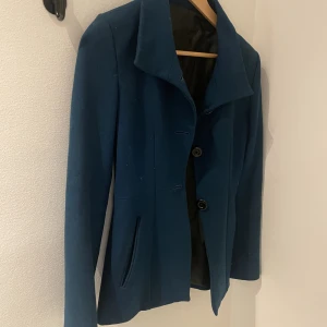 Vårjacka - Tunt fodrad jacka i en blågrön färg. Fodralformad. Legat nedpackad och därför lite smuts på men inget som inte går bort. i övrigt nytt skick. Uppskattas till storlek S men passar nog Xs också.