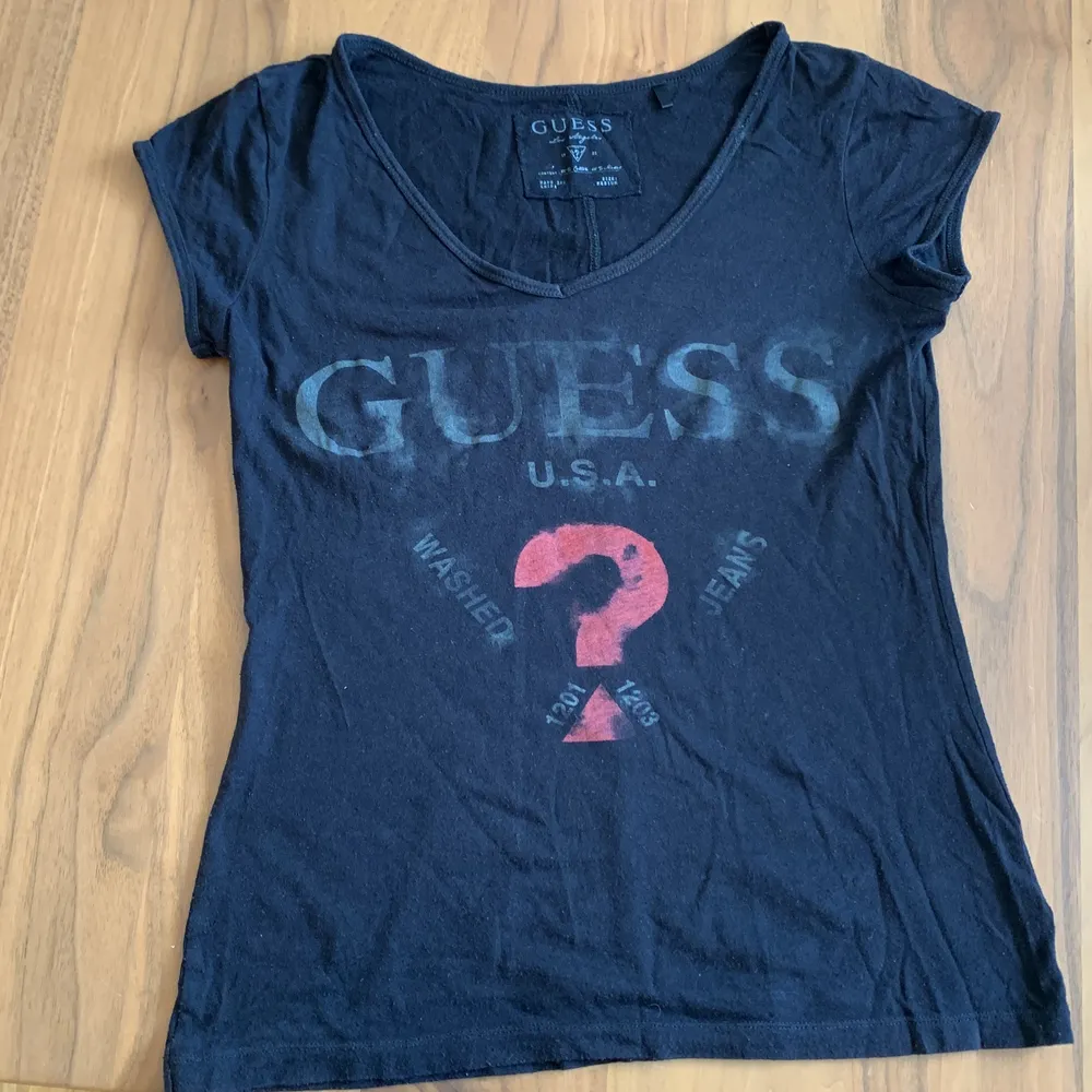 Svart Guess T-shirt i storlek medium, men passar även som S, med stort tryck för loggan på bröstet. Köpt i New York, välanvänd.. T-shirts.