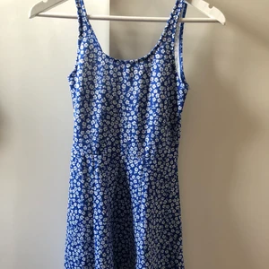 Blå blommig klänning - Klänning från hm. Köpte förra året men endast använd vid enstaka tillfällen. Lite djupare i ryggen. Strl xs