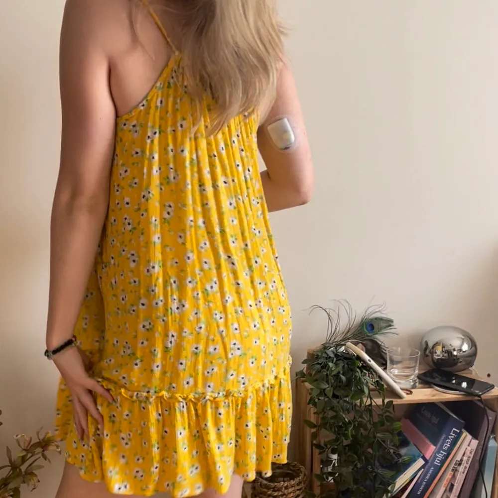 Otroligt fin och vacker gul fallande klänning med blommor. Perfekt nu under sommaren och är perfekt över en bikini. Den är lite genomskinlig i vissa ljus då det är en strandklänning. Bra kvalitet💕. Klänningar.