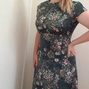 Lyxig mönstrad långklänning i en härlig grön nyans  - Klänning använd 1 gång på bal (Helt underbar). Den passar perfekt på mig (strlk 38-40) och når ner till fötterna. Klänningen är uppsydd så passar bra för den som inte har modellånga ben. Superbra skick, öppen i rygg och tyget faller jättefint. Frakt +79kr