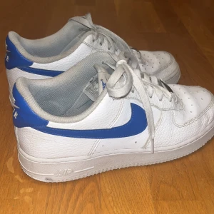 Nike air force 1 blå - Ett par snygga Nike air force 1 med blått nikemärke. Köpta för ca 1300kr. De har några defekter som syns på sista bilden (skrapmärkerna är på insidan av skon så inget man tänker på).😊