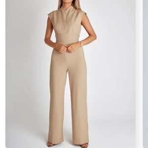 Jumpsuit  - En superskön och snygg beige jumpsuit som sitter som en smäck. Den är i storlek L men man kan bestämme hur tajt man vill att den ska sitta med skärpet. 
