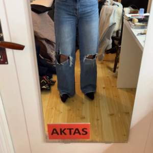 Blå jeans med hål på knäna, ett av hålen har rivits upp en del men snygga ändå! Säljer då de inte används längre