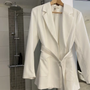 Vit blazer - En längre blazer med skärp. Från H&M och knappt använd. Köparen står för frakt
