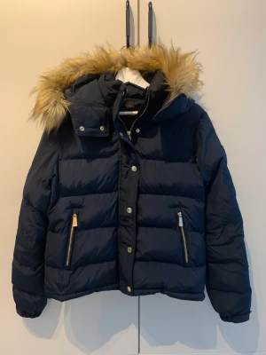 Morris vinterjacka stl.M med tillhörande mössa - Fin marinblå vinterjacka från Morris Lady. Stl M. Avtagbar päls på luvan. Ingår även en matchande mössa från Morris Lady. Jackan är sparsamt använd så den är i mycket fint skick.