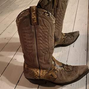 Jättesnygga cowboy boots från märket Sancho nypris 4500 kr. De är i gott skick. Skorna sitter bekvämt och är i lagom höjd. Unika i designen, köparen står för frakten då paketet blir större men packar själv så det blir lite billigare.  Knappt använda