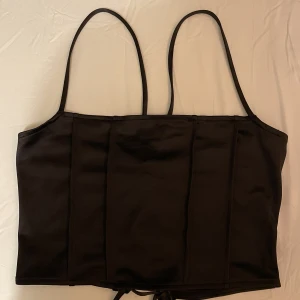 Topp från H&M, storlek M - Kort svart topp, bra skick, aldrig använd, lite korsett liknande topp