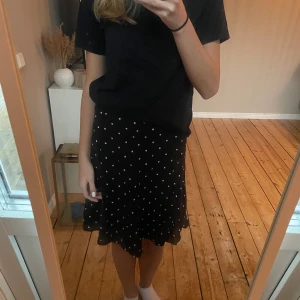 En svart prickig kjol - Säljer en oanvänd svart kjol med vita prickar i strl 34 ifrån Åhléns. Köparen står för frakten🤍
