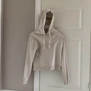 En ljusbeige hoodie från NA-KD, strl XS - En ljusbeige fin hoodie från NA-KD i nyskick! Är i storlek XS och sitter som det också. Hoodien har muddar i ärmarna och likaså midjan. Snörena som tillhör luvan är i ett flätat material. Jag kan leverera varan om köparen står för leveranskostnaderna!😊