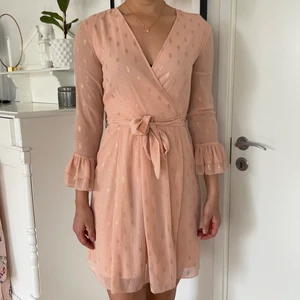 Rosa klänning - En fin rosa klänning i omlottmodell med guldiga prickar och knytning i midjan. Lamporna sitter fortfarande kvar. Storleken är 36 och jag är 178cm lång  