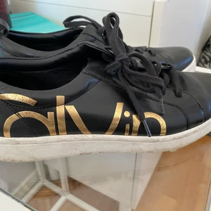 Calvin Klein - Superfina svarta lågskor från Calvin Klein, vit sula text på varje sida av skon i guld. Använda ett fåtal gånger så fint skick. Storlek 40. 