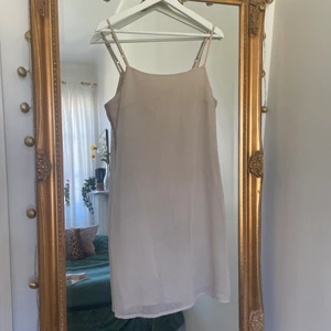 Klänning - En beige klänning som går till mitten av låren. 