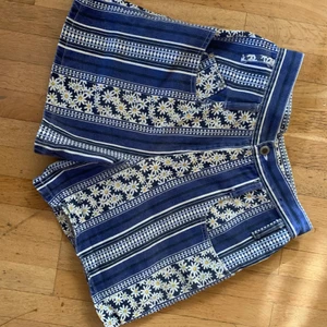 Jeansshorts 90s Blommiga Festival Jeans - Söta 90-tals jeansshorts, helt oanvända. Strl36, måttar gärna. Fint skick. Pris inkl spårbar frakt.