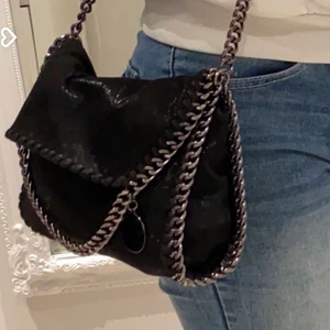 Stella Macartney liknande väska - Säljer nu denna super fina väska som liknar stella Macarteney🖤 den är använd men det finns inga defekter på väskan🖤 rymlig och snygg till allt🖤 glittrig i tyger och mörk kedja🖤 kan tänka mig att byta mot någon annan liknanden väska🖤