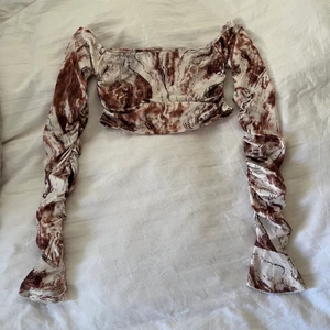 Helt ny mönstrad croptop strl S - Helt ny, aldrig använd mönstrad croptop. Vit och brun, rynkad i sidorna och på ärmarna. Frakt 52kr🥰