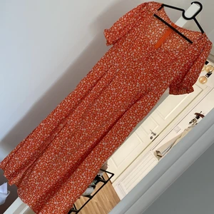 Långklänning  - Orange blommig långklänning med dragkedja på ryggen. Säljes pågrund av fel storlek  St 40 - 42 Köparen står för frakt