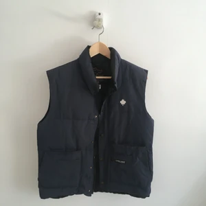 Vest från Canada Goose - Vintage, mörkblå vest av märket Canada Goose. Storlek XS enligt lappen, men sitter som storlek small. Okej skick med tecken på användning.