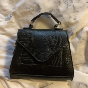 Väska  - En liten svart väska som är köpt från Nelly men kommer inte till använign längre. 