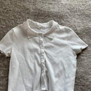 Här är en vit magtröja som liknar en skjorta. Jag säljer denna för att jag aldrig använder den. Den är i storlek 152 och passar för dom som är i åldern mellan 12-13.
