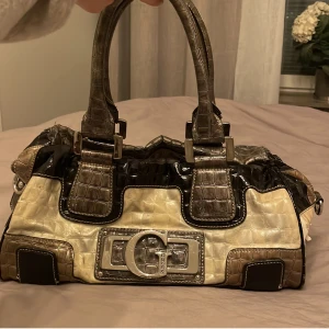 Guess väska - Snygg väska i bra skick som rymmer mycket. Köpt här på Plick men jag säljer då den inte kommer till någon användning. Tyget har lossnat lite på sidorna (bild 2&3) och finns några få missfärgningar, men är inget som syns tydligt. Pris kan diskuteras💗