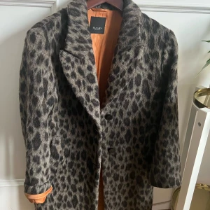 Leopardmönstrad kappa från Sand -  Leopardmönstrad kappa från Sand. Tillverkad i ullmix. Två snedställda fickor, en innerficka. Orange foder. Stl 34 men passar en 36/38.   Nypris 4499kr säljer för 2300kr. Använd ett fåtal ggr så ser ny ut.   