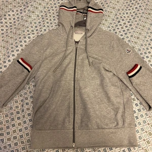 Moncler Hoodie - Säljer nu mina älskade grå Moncler Tri color zip i grymt skick, nästintill oanvänd. Storlek M och sitter tts om inte lite större. Behåller hellre men släpper om jag får bra bud. Slutsåld modell samt färg, nypris går på 4500 sek. Bud över 3000 sek, ÄKTA