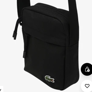 Lacoste axelremsväska svart - En sällan använd väska från lacoste nypris var 775kr. Frakt tillkommer. Egna bilder kan skickas vid förfrågan.