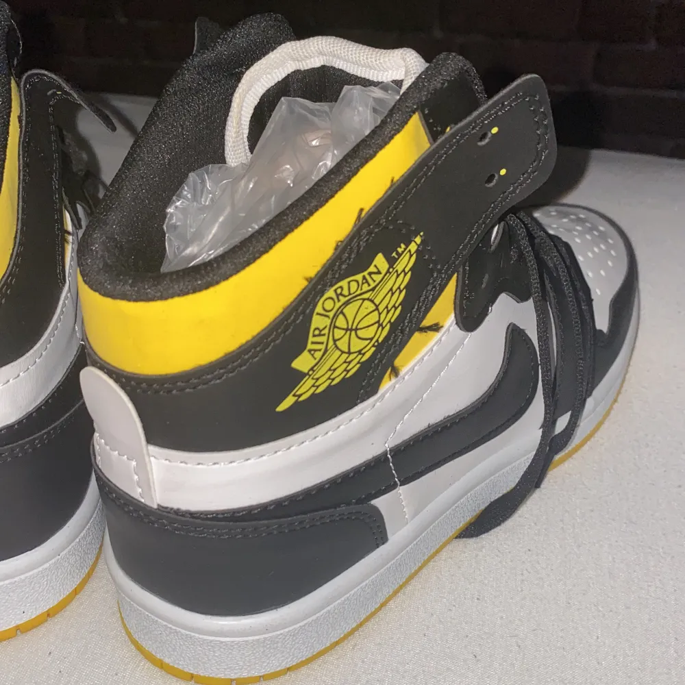 Jordan 1 skor kopia helt nya och har färg gul svart vit. Skor.