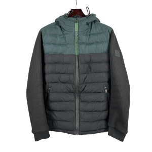 Grön/svart hybridjacka - Hybridjacka från Hugo Boss i en grön och svart färg.   Plagget har en normal passform.   Mått, i cm: Bröst: 124 Midja: 120 Stuss: 116 Rygglängd: 73 Ärmlängd: 70