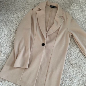 OVERAIZED BLAZER BEIGE XS - Säljer denna snygga blazern i mjukare material. Supersnygg, oversized. Storlek 34. Från prettylittlething. Aldrig använd helt nytt skick. Perfekt till fest eller som vår / sommar kavaj. Säljer för 100 kr. Köparen står för frakten! 