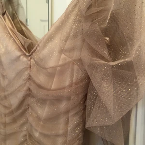 Glittrig klänning - Supersöt puderrosa, glittrig klänning! Köpt på prettylittlethings för några år sedan, men aldrig använts, prislapp kvar. Storlek 38