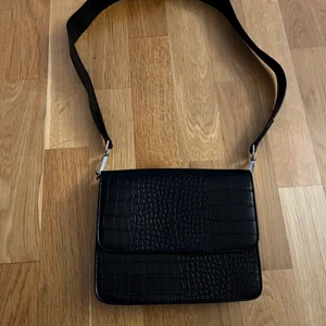 Svart Axelremsväska  - Väskan är köpt från Gina Tricot. Väskan är inte så bredd men däremot djup så allt som är nödvändigt får absolut plats. Väskan köptes för 239kr💕