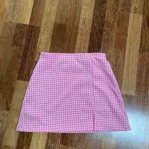 Rosa kjol - Rosa ginghamkjol från pull and bear i strl L och aldrig använd. Säljer pga fel storlek och  köpt förra året. Köpte för 199 kr mitt pris är 69 och som sagt aldrig använd.