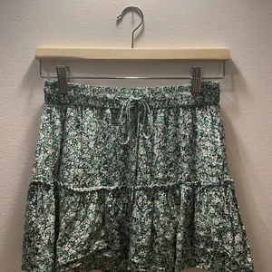 Volang kjol  - En jättefin grön volang kjol med inbyggda shorts från zara. Kjolen har ett jättefint blommig mönster:)