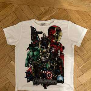 Vit T-shirt med Avengers tryck. Den är liten i storleken, S ungefär, lite som en croppad tea. 