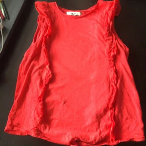 Hampton Republic No sleeve red shirt size 158-164 cm - A red no sleeve shirt with a tie at the bottom. A puffy design that goes along the shoulders and all the way down for both sides (back and front).