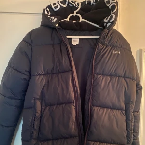 Hugo Boss dunjacka  - Så snygg Hugo Boss jacka i stl 14. Motsvarar 170 eller stl. S skulle jag säga. Köpte den till min son i present men han har aldrig någonsin använt den. Jag är 167 cm lång, 57 kg. Nypris 2600:- 🥰