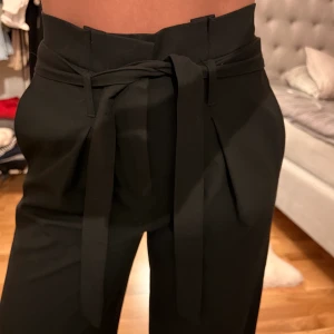 Svarta kostymbyxor - Svarta kostymbyxor från Only. Storlek 36. Raka ben. Snörning för bandet går att ta av.