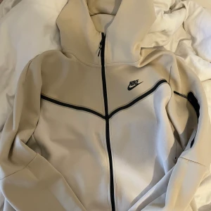 Nike tech fleece - Säljer denna beiga Nike tech fleece koftan i storlek L. Den passar dock inprincip de flesta beroende på hur man vill att den sitter. Beställdes från Nike’s egna hemsida för 2/3 månader sedan och har endast använts 3 gånger. Skriv vid intresse 66kr=frakt