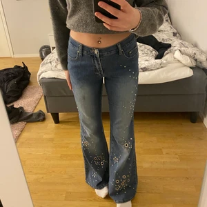 Lågmidjade jeans med silver ”mönster” - säljer ett par lågmidjade jeans med silver mönster eller detaljer, storleken är M och tyvärr har de någon fettfläck som inte verkar gå bort. köparen står för frakten💕💕