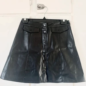 Svart kjol i skinnimitation - A-linjeformad minikjol från hm. Skinnimitation. Med knäppning. Nyskick. 