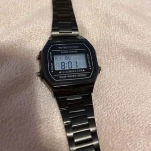 Digital handklocka  - Säljer nu denna snygga retroklocka i svart metall. Klockan har en digital urtavla med datum, belysning, tidtagning samt alarm vilket betyder att du kan sätta datum och alarm på den, ta tid med den och den har också en lampa om du skulle behöva se när det är mörkt…. Den är även vattentät. Fick den i födelsedag men har nästan aldrig använt den eftersom jag har så pass många klockor så den är i helt ny skick. (Köparen står för frakten) 