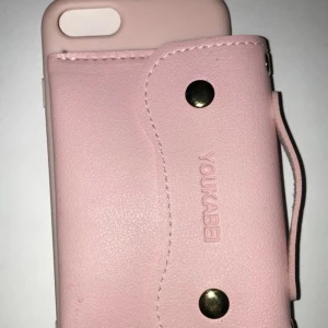 7/8Rosa mobil skal + en väska på, Fyndiq - Ljus Rosa, skal med en väska som fungerar som en plånbok. Får plats med kontanter och typ två kort exempel ditt busskort eller ditt kort. Den är väldigt effektiv och fin. På väskan finns ett band och två guldiga knappar som öppnar väskan. 7/8 IPhone SE2