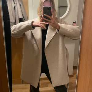 Kort kappa NAKD - En halvlång beige kappa från nakd i ullblandning perfekt nu till vintern, knappt använd så den är som ny!! Skriv för fler bilder💕