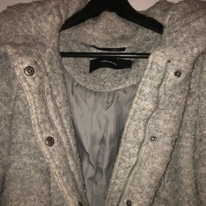 Grå kappa  - En grå kappa från veromoda. Köpt för 1999kr men säljer för 700kr. Kappan ger ner till början av knäna. Tjock material med stor luva. Funkar att knäppa med dragkedja och knappar. Finns två stora fickor.