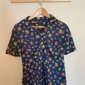 Blommig 70-tals blus , storlek S - En härlig 70 tals blus! Kortärmad så passar perfekt till sommaren och våren! Känns som ny. Passar XS-S. Står inget om material men gissar på lyocel eller liknande material. 