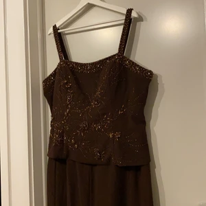 Klänning - En brun festklänning som är köpt för 1000kr men säljs här för 500kr, använd endast 1 gång, alltså som ny. Med klänningen får man en matchande kofta som köptes tillsammans med klänningen                                                 Den är i storlek 3XL men passar även en  XLL                                Om ni vill ha flera tydliga bilder eller har frågor kontakta mig!    Frakt tillkommer! 